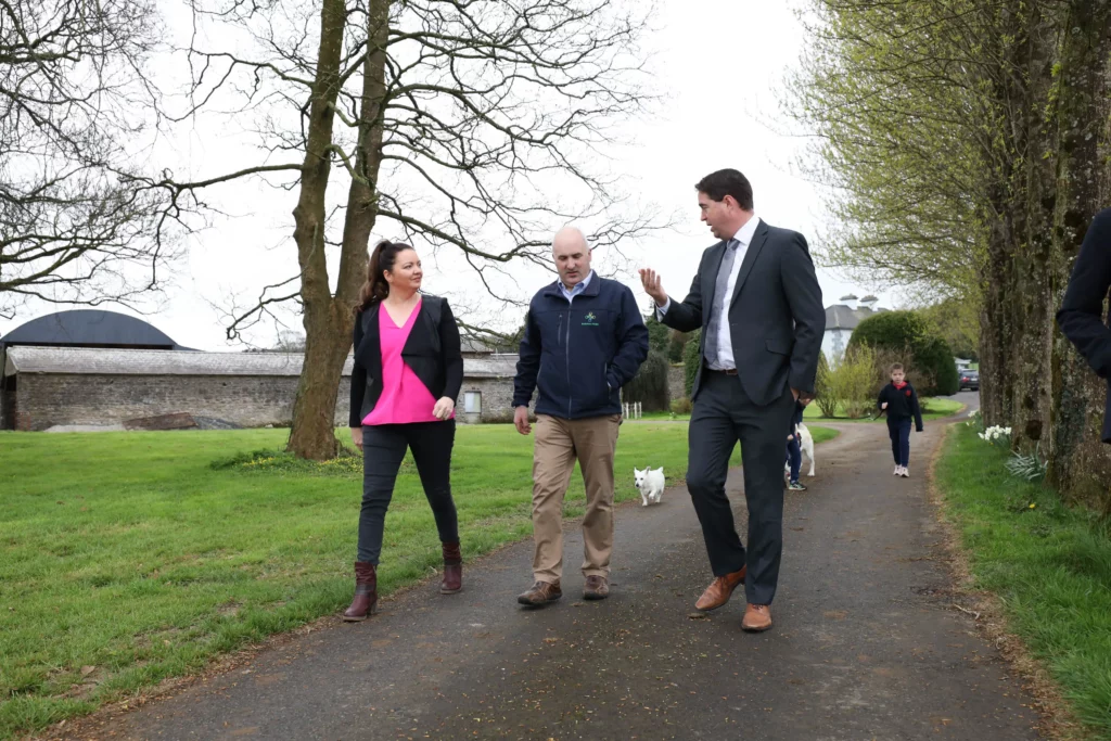 Three individuals engaged in a casual business conversation while walking in a green area